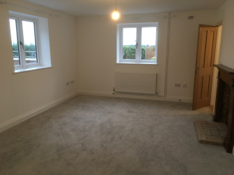 Living Room, showing wood-burning stove and fireplace, looking towards bathroom